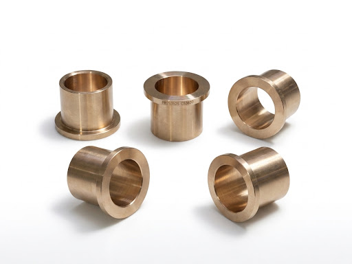 Flanged bronze bushings for axial location and heavy equipment assemblies